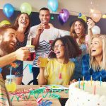 Happy exuberant group of friends celebrating a birthday party toasting the birthday girl laughing and joking